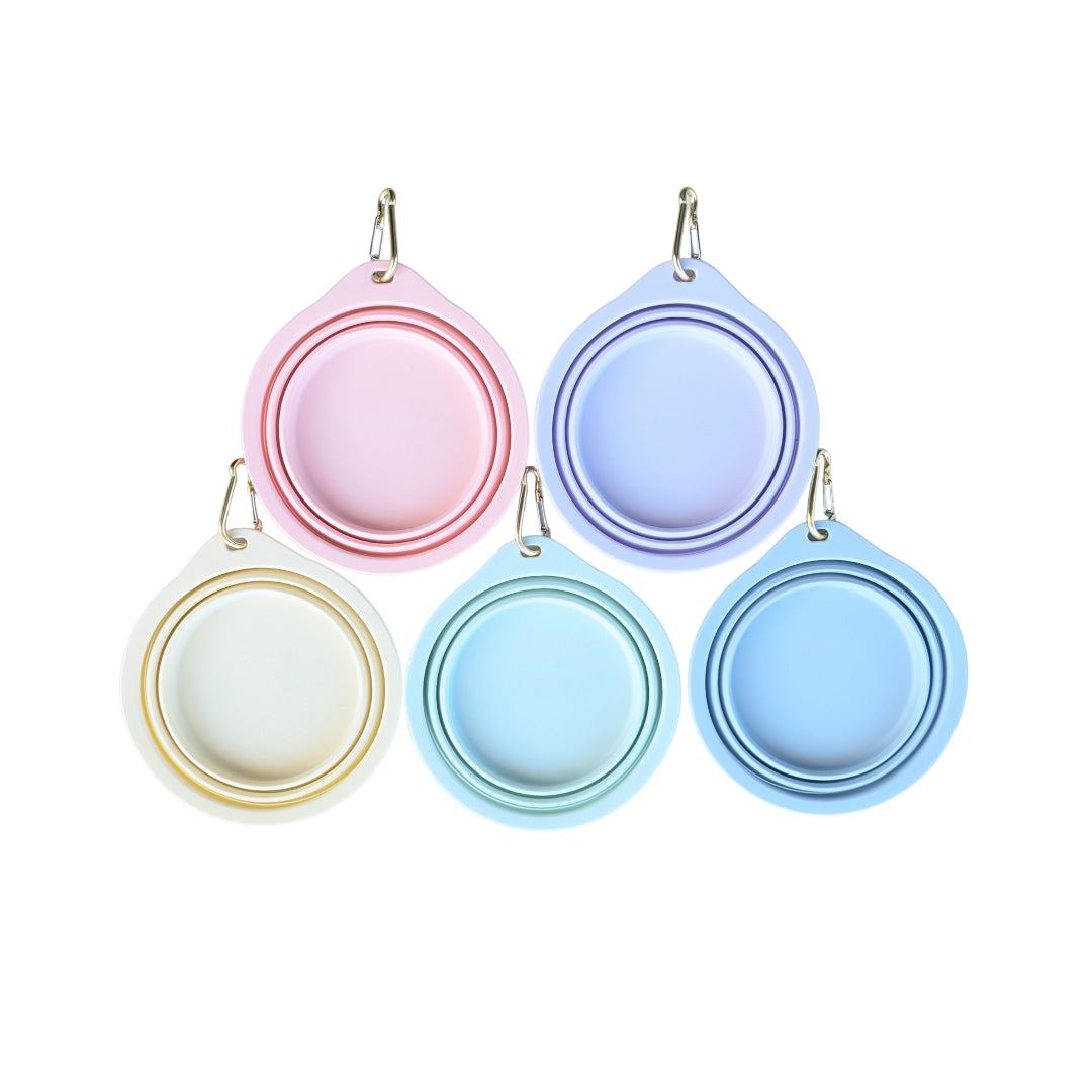 Fünf gefaltete, runde Reisenäpfe in Pastellfarben (Gelb, Mintgrün, Blau, Rosa, Lila) mit Karabinern auf weißem Hintergrund
