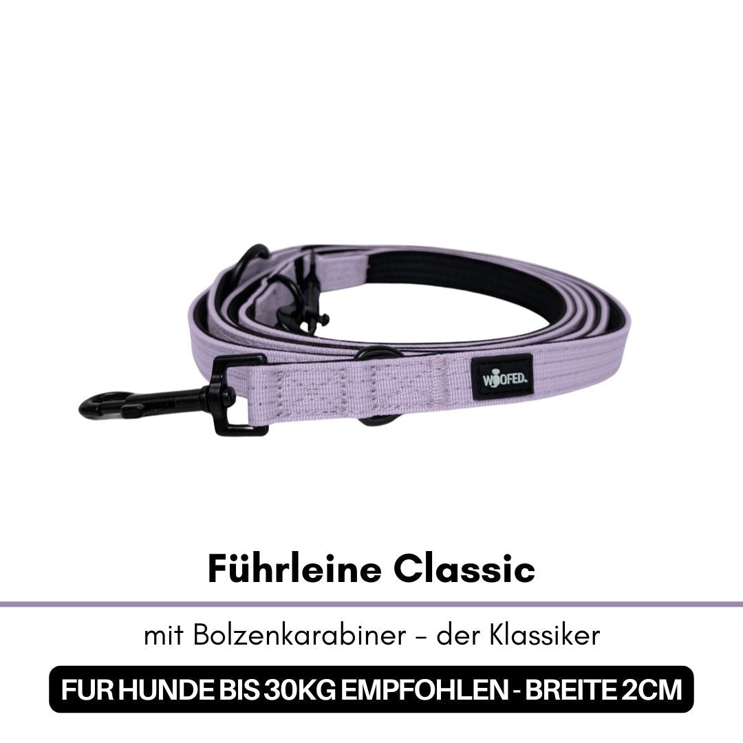 Aufgerollte lilafarbene Führleine Classic mit schwarzem Bolzenkarabiner, schwarzer Innenkante und WOOFED-Label, Nahaufnahme