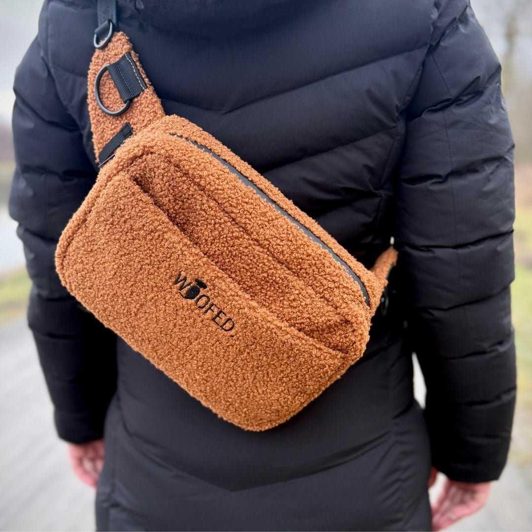 Braune Teddy-Gassitasche quer auf dem Rücken getragen, gesticktes WOOFED-Logo, schwarzer Reißverschluss und D-Ring