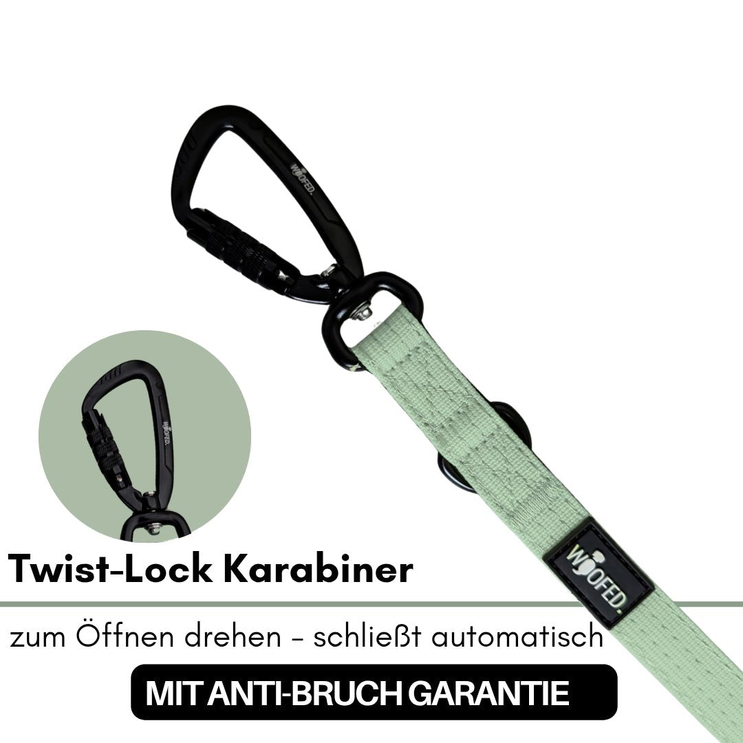 Sagegrüne flache Nylon-Leine mit schwarzem Twist-Lock-Karabiner, zwei schwarzen Ringen und WOOFED-Label, schräge Draufsicht