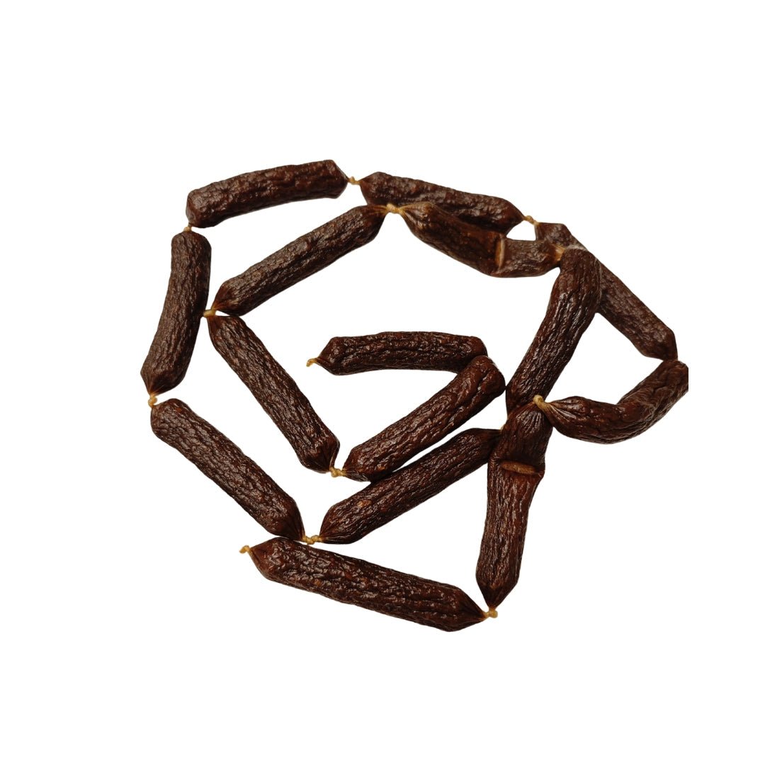 Dunkle Rinder-Würstchen (9 cm) für Hunde, aneinandergereiht in Spirale auf weißem Hintergrund, Draufsicht