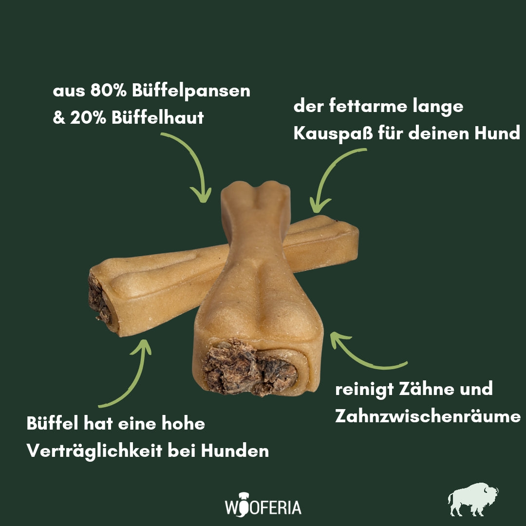 Zwei hellbraune Pansen-Kauknochen überkreuzt, Nahaufnahme vorn mit sichtbarer dunkler Füllung auf grünem Hintergrund