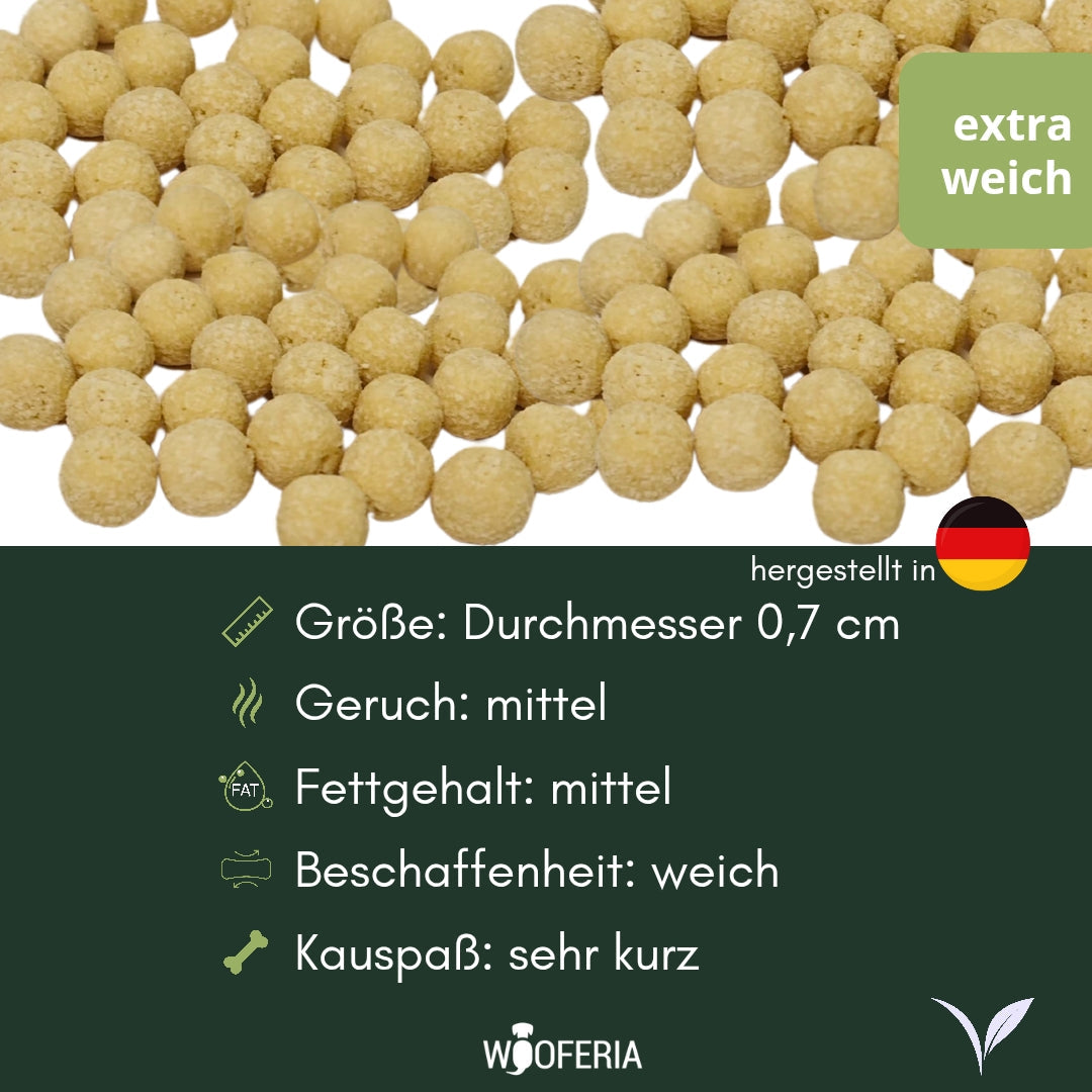 Nahaufnahme vieler beige Kokos-Soft-Kugeln (Ø 0,7 cm) mit grünem ‚extra weich‘-Label und Infotafel unten