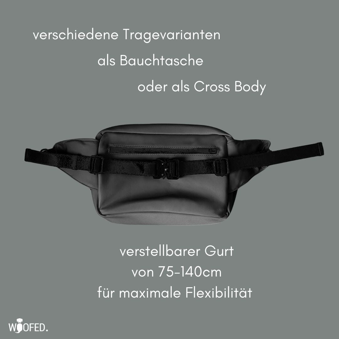 Graue Gassitasche, frontal liegend, ausgestreckter verstellbarer Gurt mit Klickverschluss und vordere Reißverschlusstasche