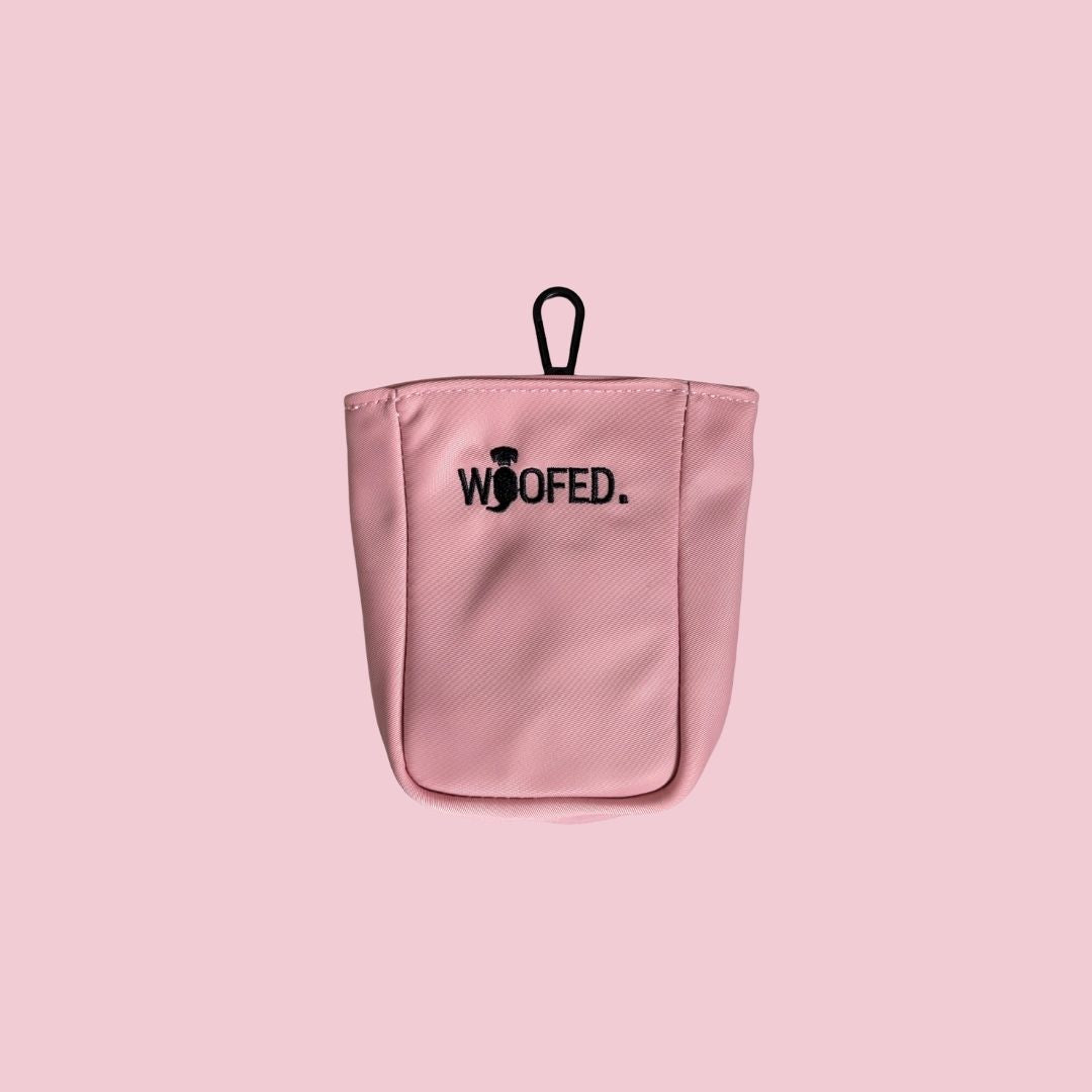 Rosa Leckerlibeutel, Frontalansicht, abgerundete Form, schwarzes gesticktes „WOOFED.“-Logo und schwarzer Befestigungsloop auf