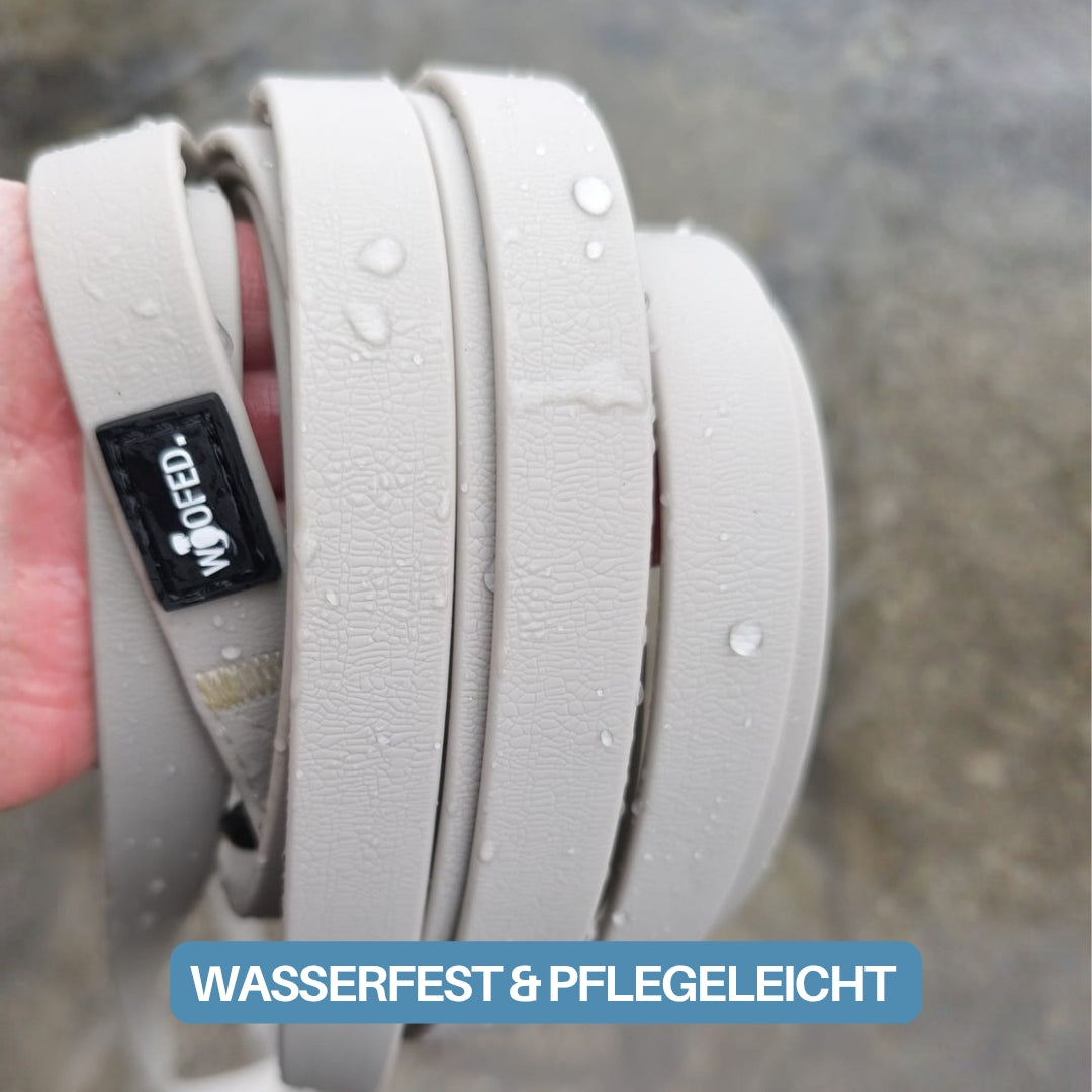 Beige WOOFLEX Schleppleine Desert Sand, Nahaufnahme, gerollt in Hand, sichtbare Wassertropfen auf texturierter Oberfläche