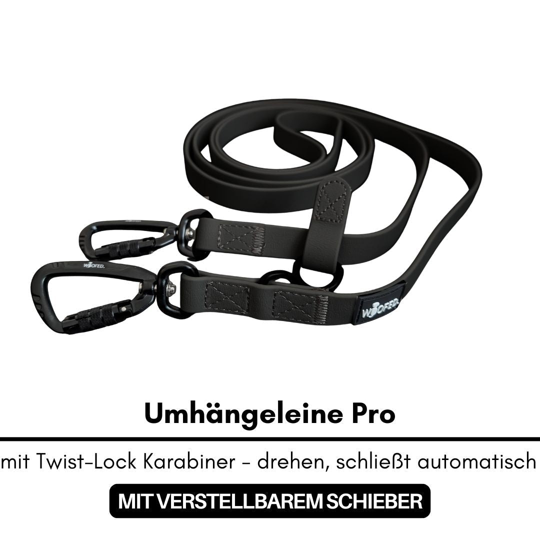 Schwarze Umhängeleine flach aufgewickelt mit zwei schwarzen Twist‑Lock‑Karabinern, verstellbarem Schieber und WOOFLEX‑Label