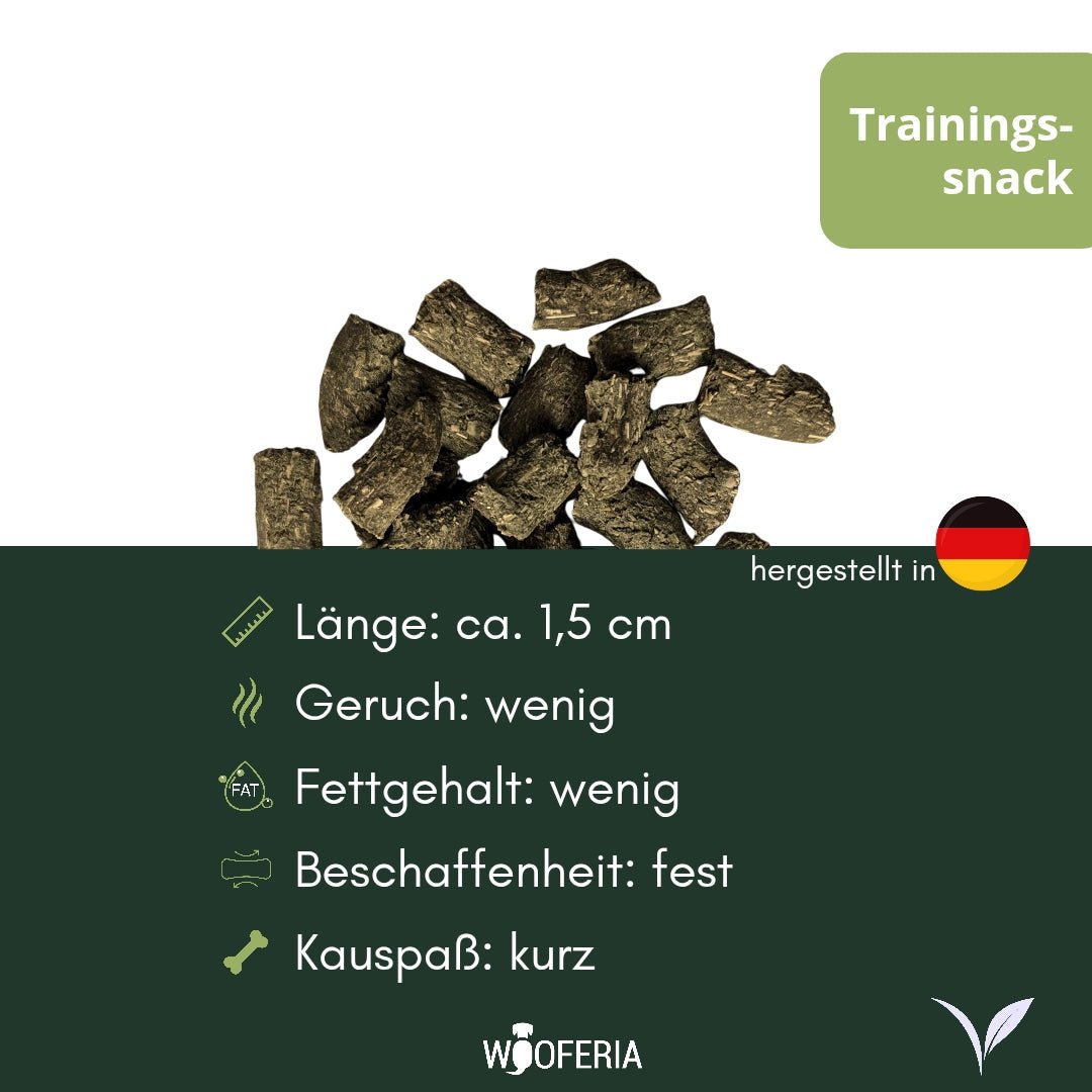 Kräuter Trainingssnack: Haufen dunkelbrauner, unregelmäßiger Stückchen (ca. 1,5 cm), Draufsicht auf weißem Hintergrund