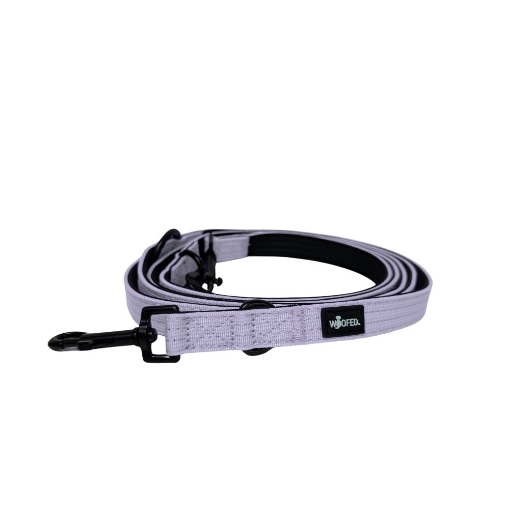 Aufgerollte lilafarbene Nylon‑Führleine, schwarze Innenpolsterung, schwarzer Karabiner und WOOFED‑Label, flach aufgenommen
