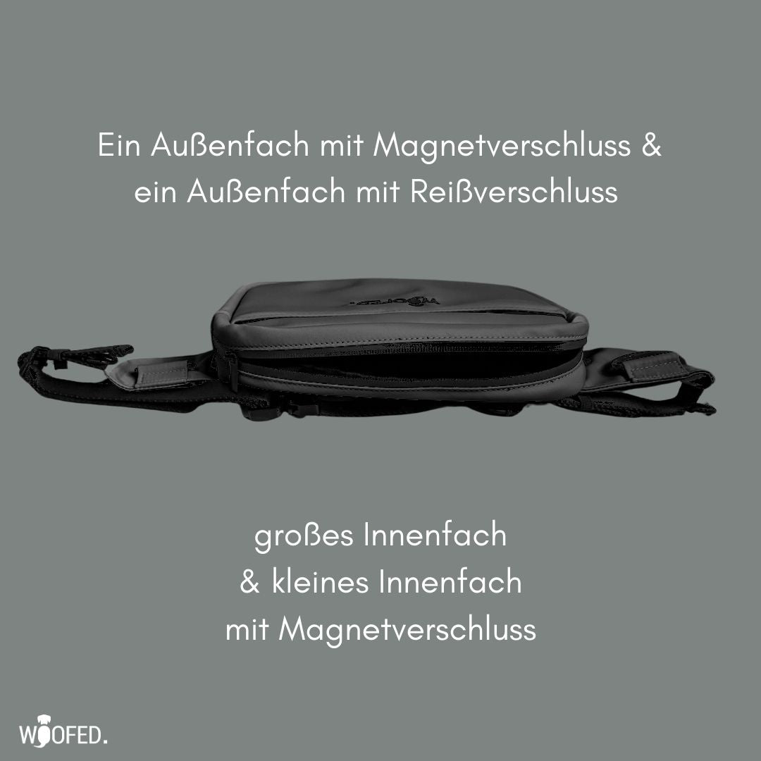 Graue Gassitasche liegend, seitliche Ansicht mit geöffnetem Reißverschluss, flaches Profil und verstellbarem Gurt