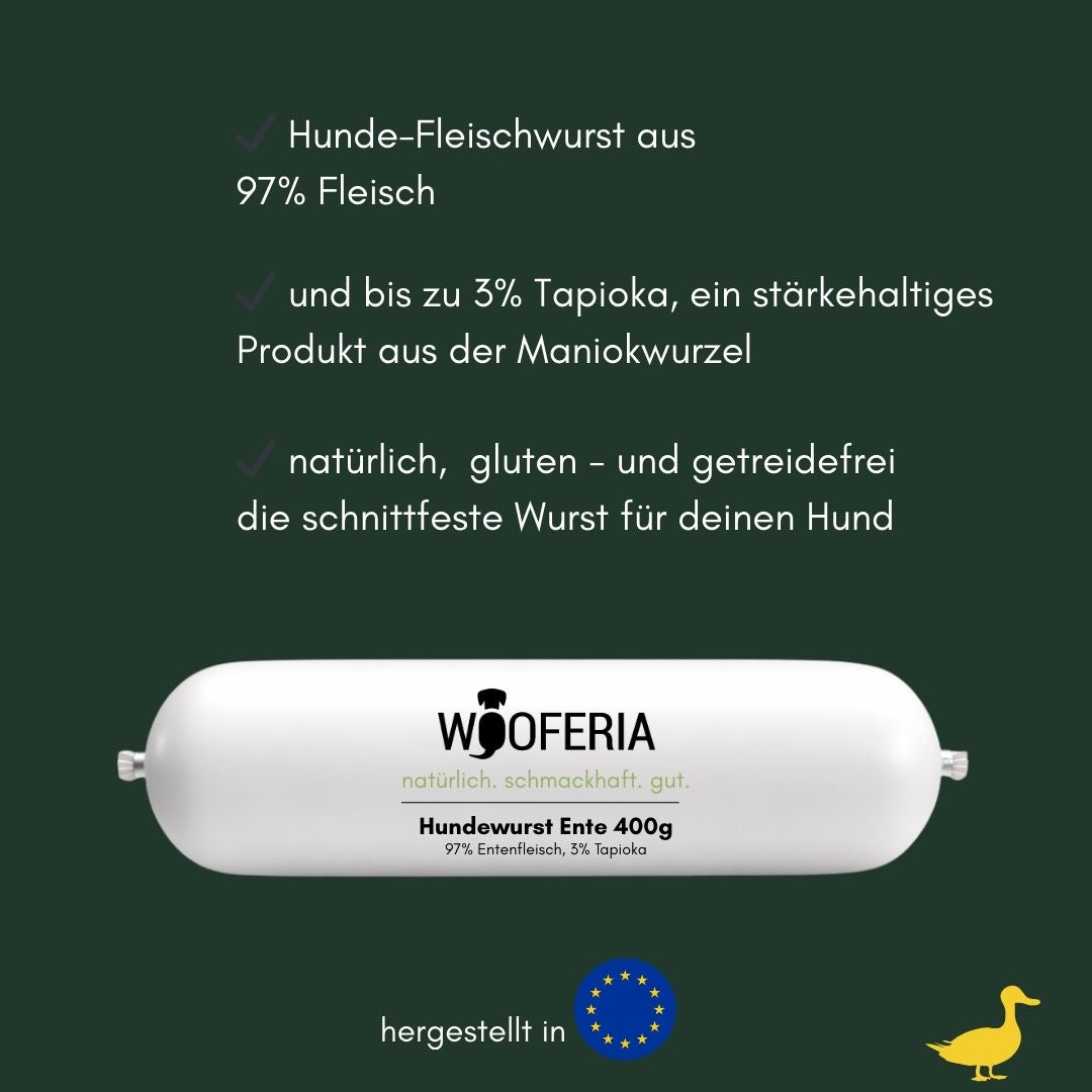 Weiße längliche Hundewurstverpackung mit WOOFERIA-Logo auf dunkelgrünem Hintergrund, EU‑Flagge und gelber Enten‑Silhouette