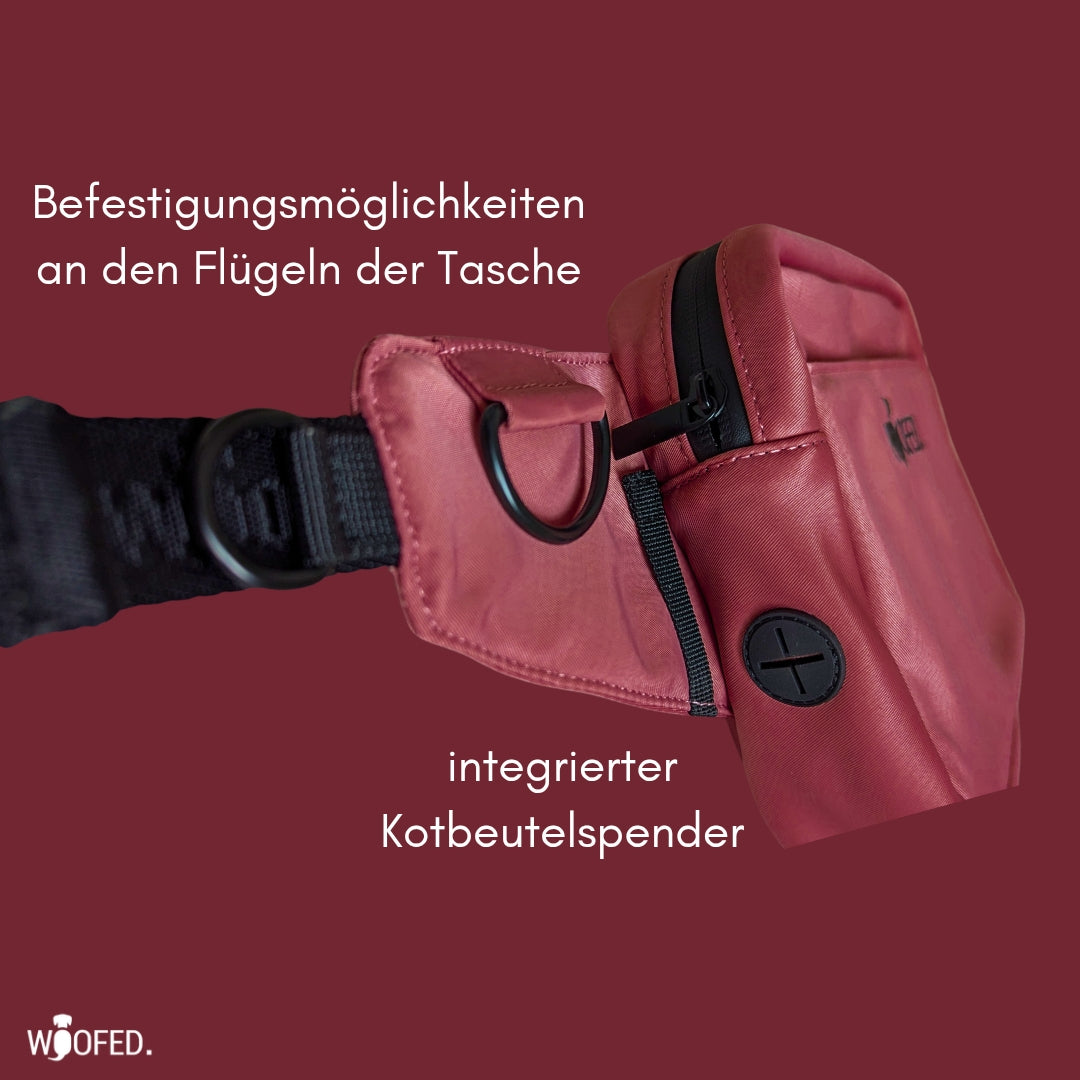 Seitliche Nahaufnahme rote Gassitasche (Wine Red) mit D-Ring, schwarzem Gurt und integriertem Kotbeutelspender